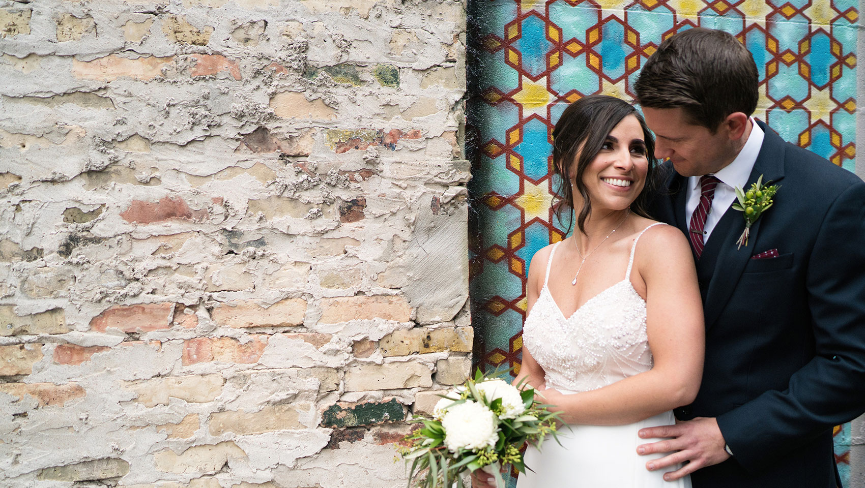 Couple in front of brick wall and mosaic