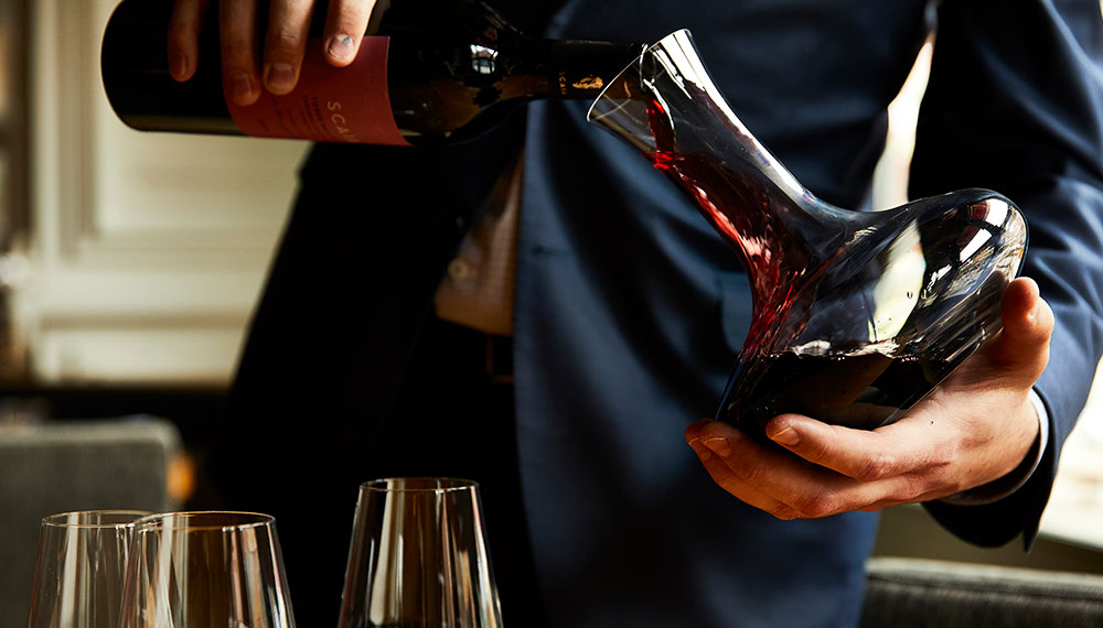 person pouring a bottle of red wine into a decanter